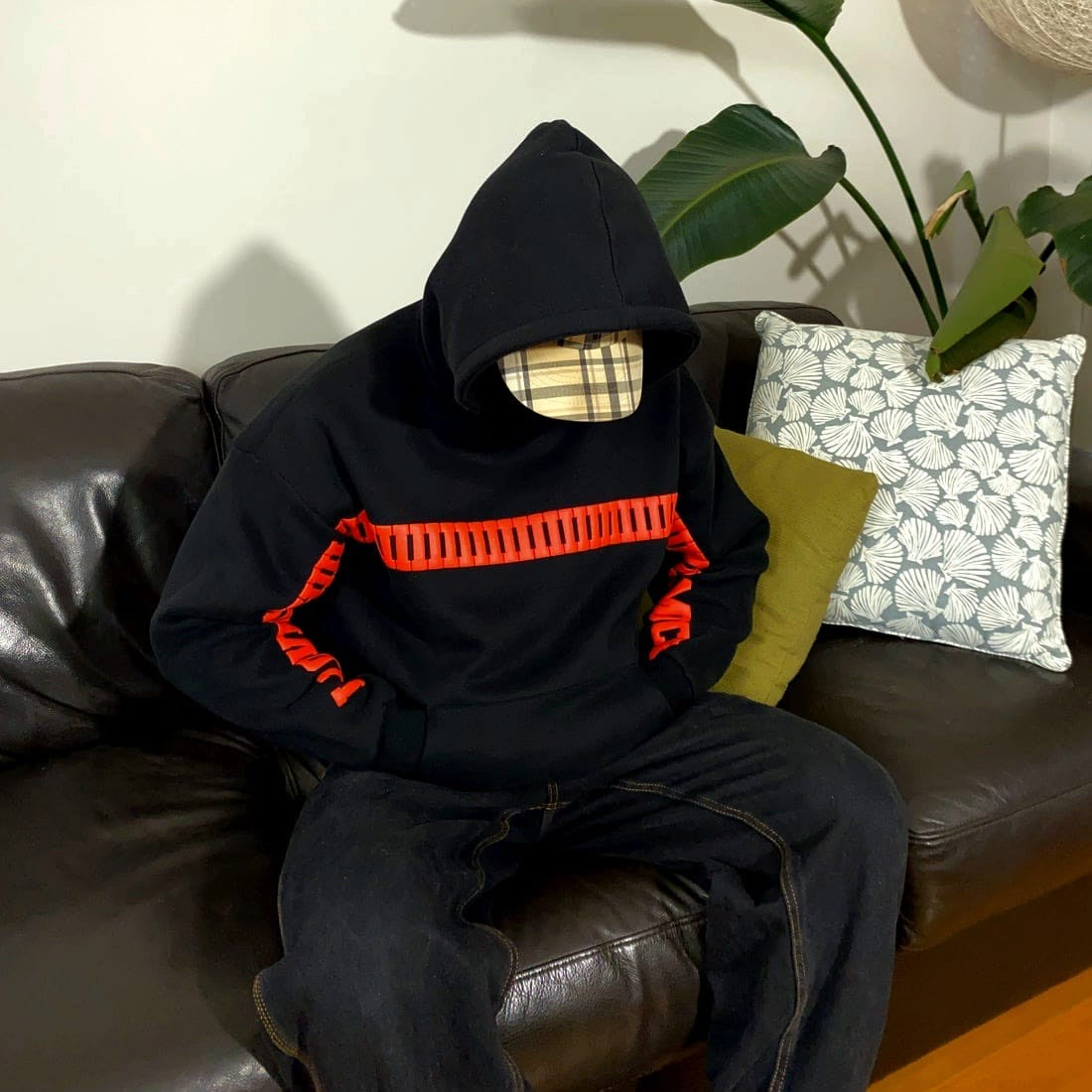 Person wearing a I Love You This Much Hoodie by Gigavibe with red accents sitting on a brown leather couch.
