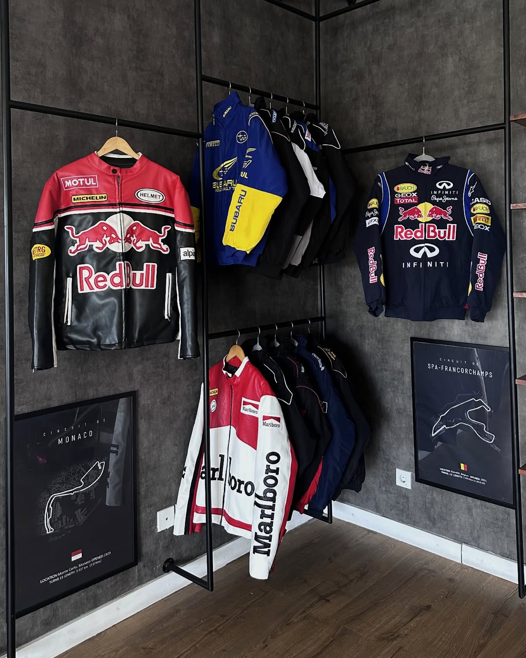 gigavibe Collection of racing jackets on hangers against a dark wall with framed posters.