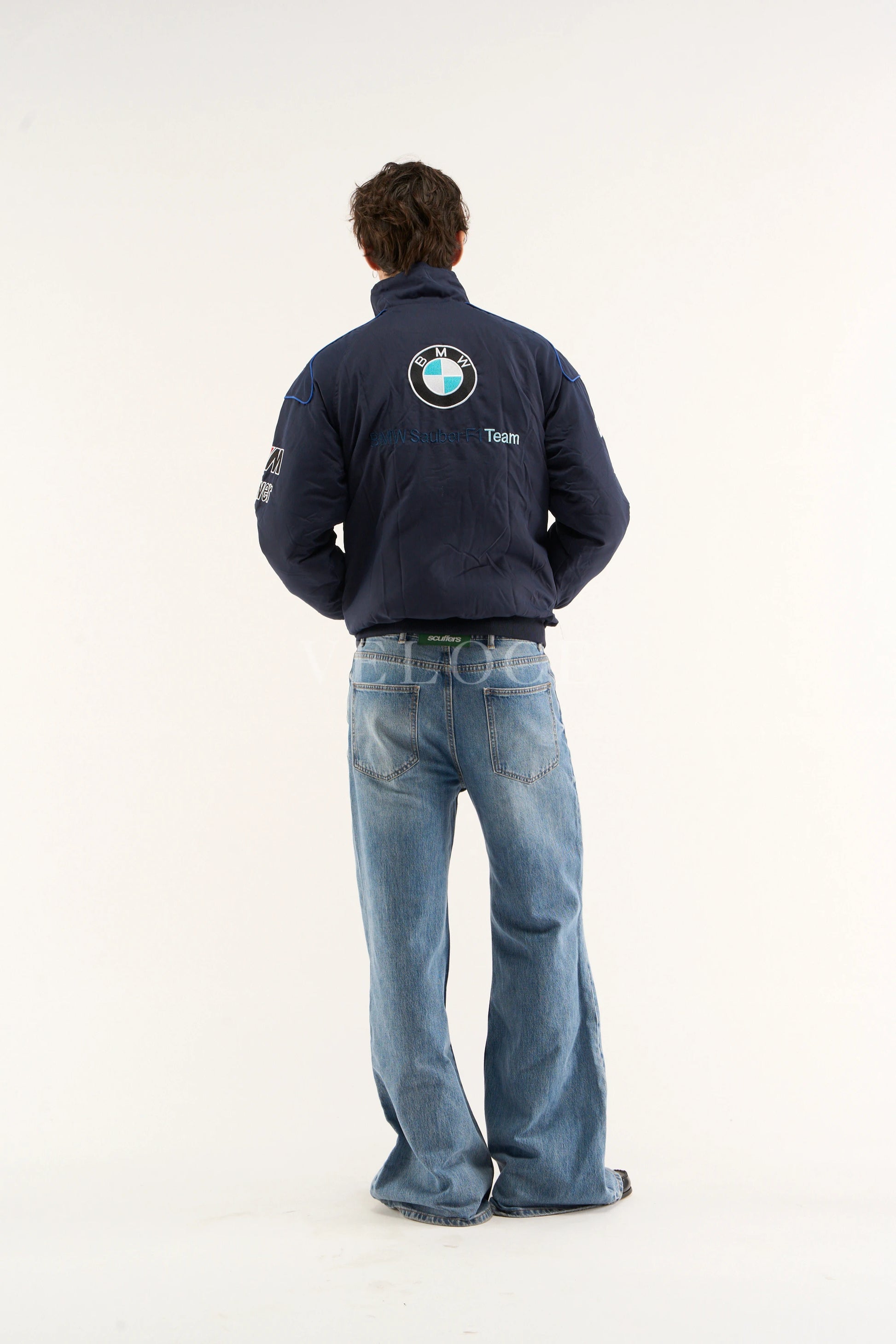 Person wearing a BMW Petronas Racing Jacket Premium Printed Designwith a BMW logo on the back, standing against a white background