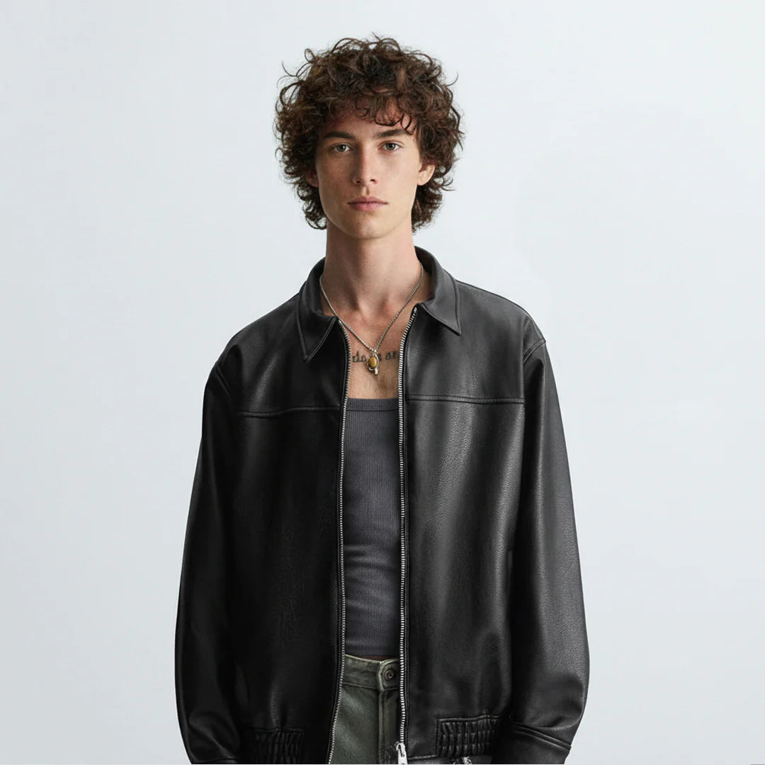 Front view of black leather bomber jacket worn by model, featuring zipper closure and modern biker style design