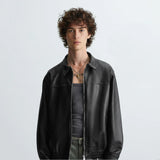 Front view of black leather bomber jacket worn by model, featuring zipper closure and modern biker style design