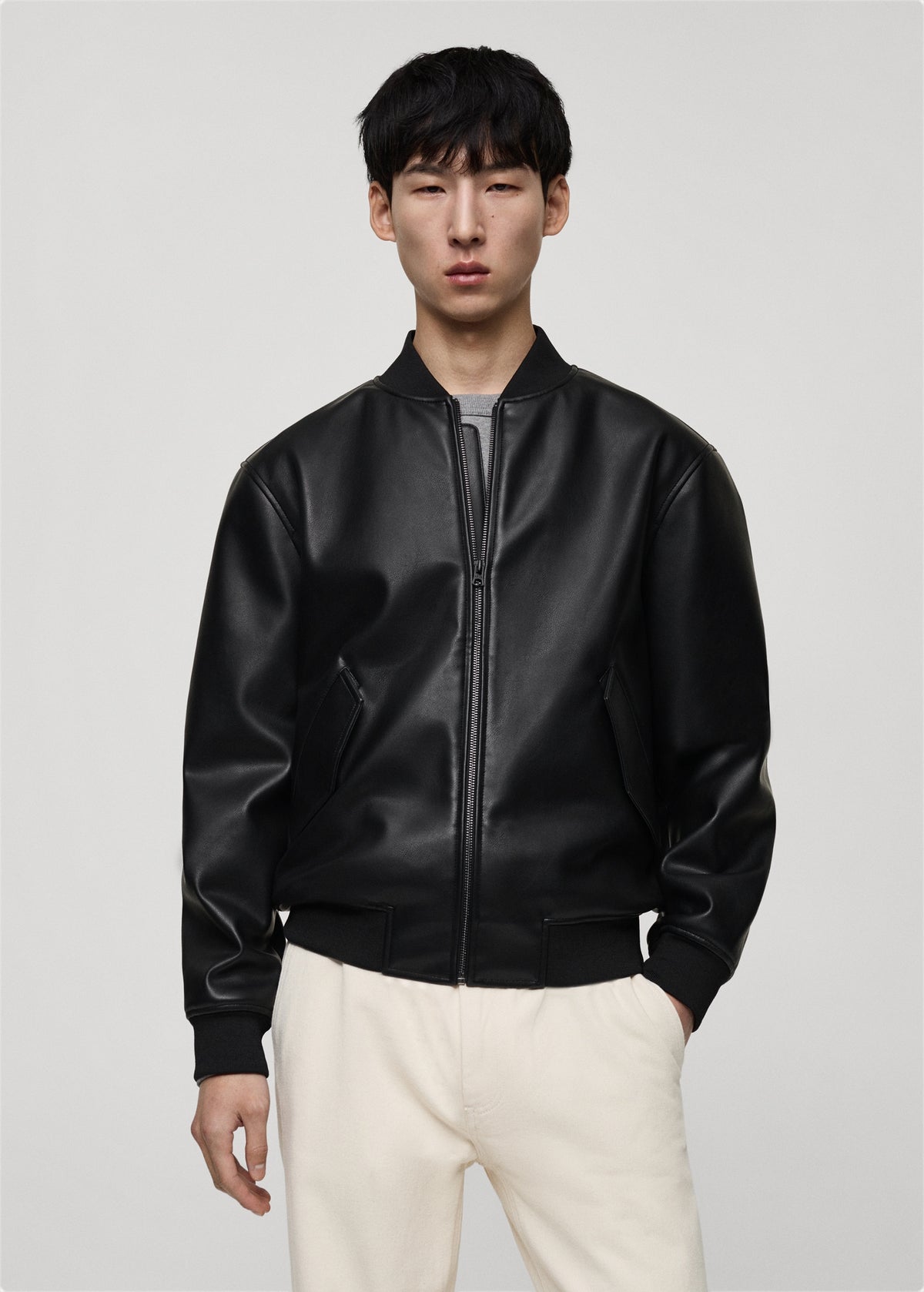 Model wearing a Premium black leather bomber jacket with classic bomber style fit on a plain background