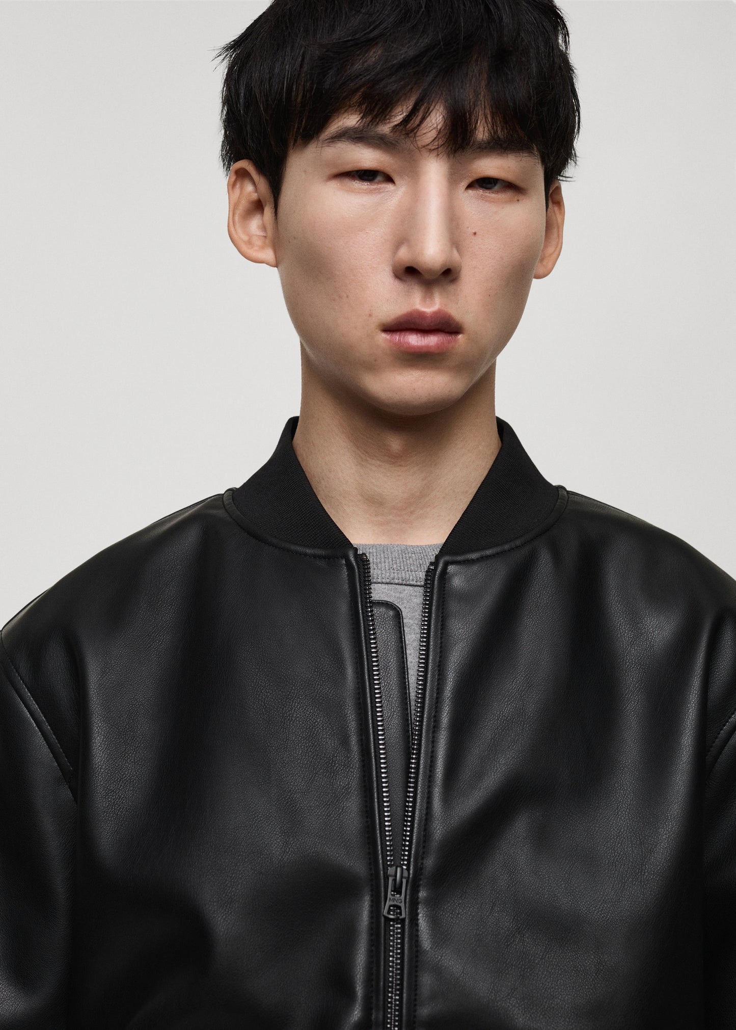 Close-up front view of Gigavibe Black Leather Bomber Jacket zipper and collar