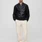 Front full-body shot of Gigavibe Black Leather Bomber Jacket styled with white pants