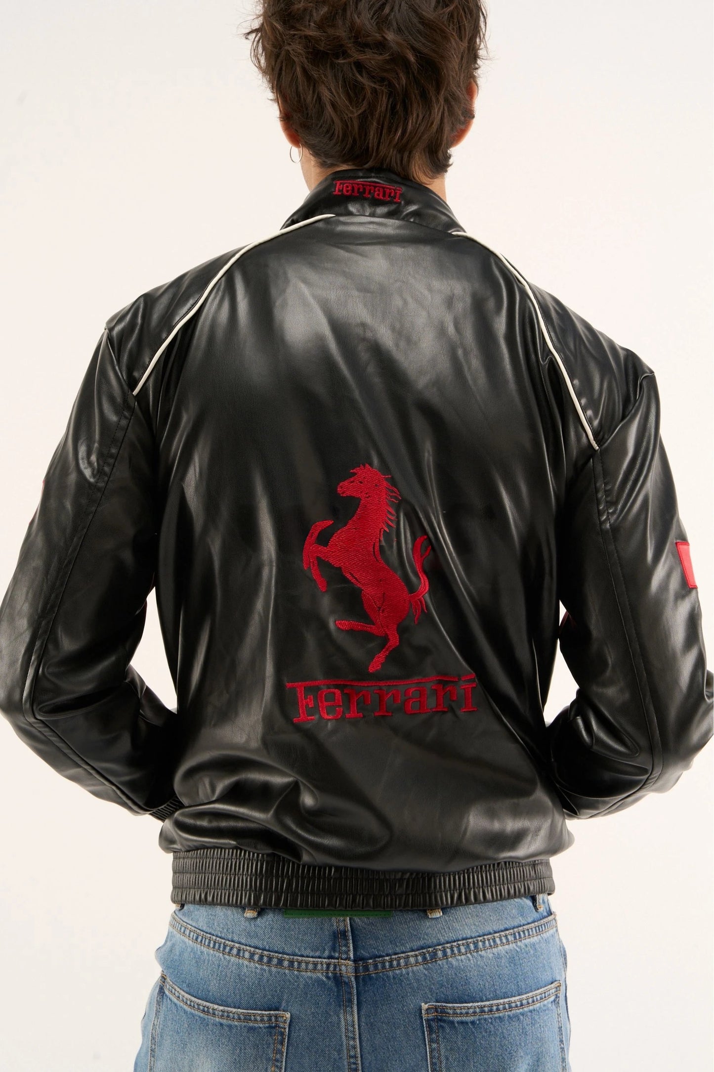 Back view of black Ferrari leather jacket with red embroidered logo and motorsport-inspired racing design
