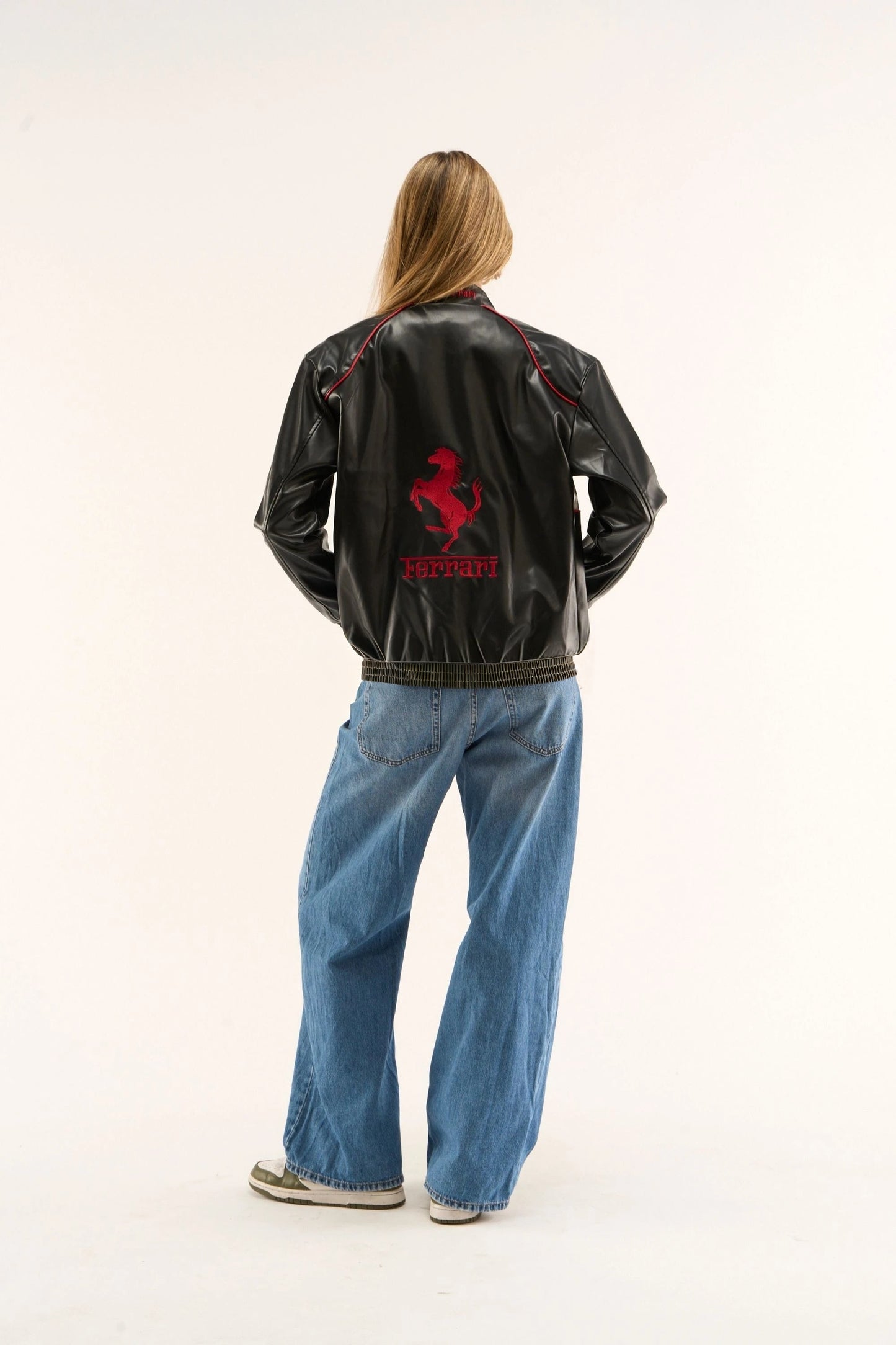 Back view of black and white Ferrari leather jacket showcasing bold Ferrari logo and racing silhouette