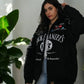 Women wearing a Jack Daniels jacket front view with premium logo print standing next to a plant.