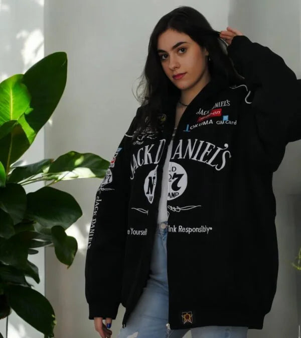 Women wearing a Jack Daniels jacket front view with premium logo print standing next to a plant.