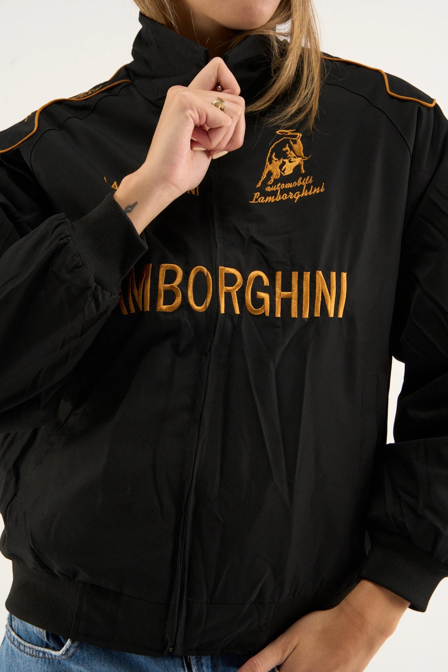 Close-up view of Gigavibe black Lamborghini jacket embroidered with gold logo and text on parachute fabric.