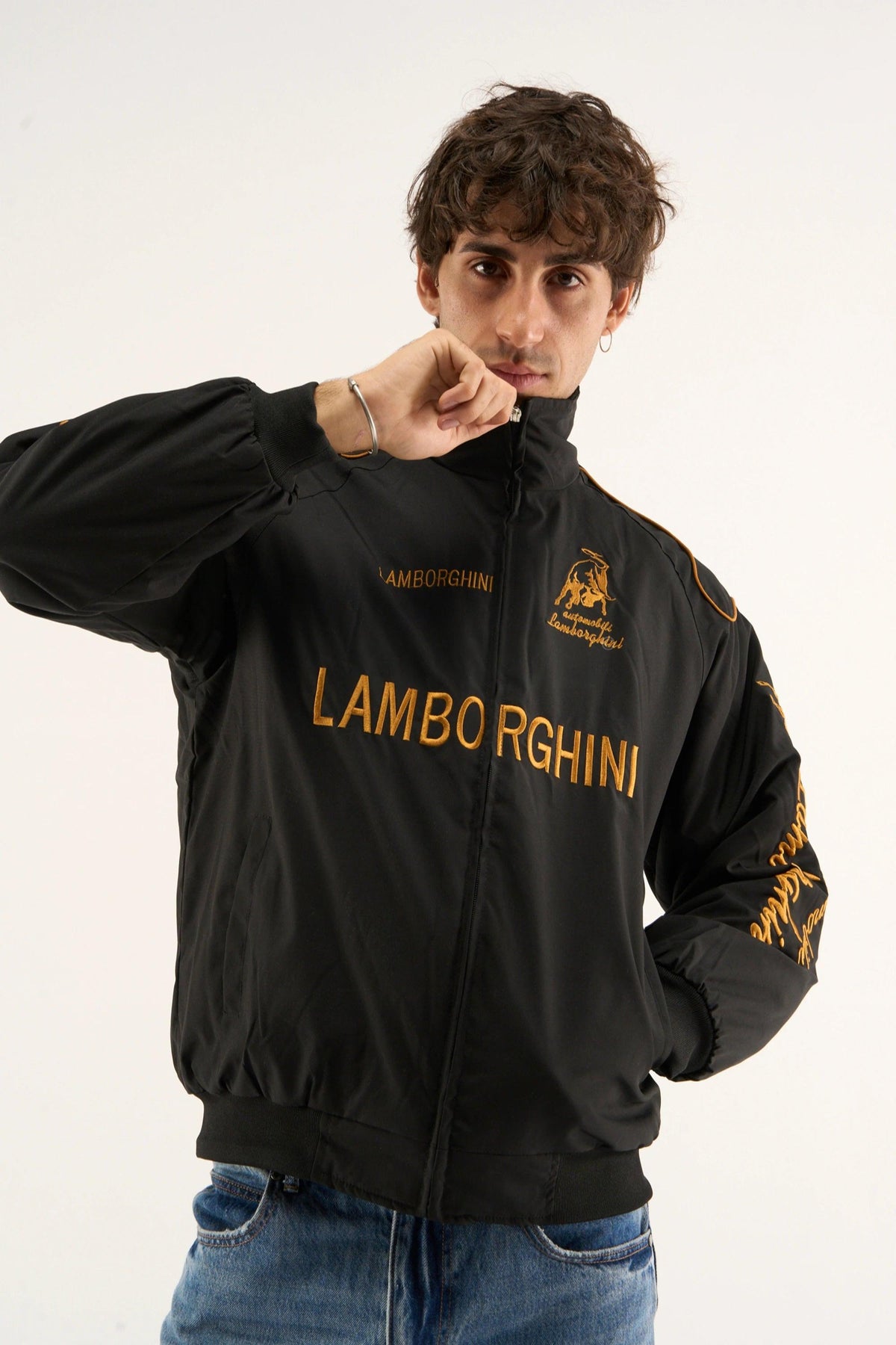 Male model wearing Gigavibe Lamborghini jacket embroidered black racing jacket with gold detailing and high-neck design.