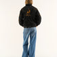 Women wearing a Lamborghini embroidered jacket women’s luxury streetwear look with a logo on the back, standing against a white background