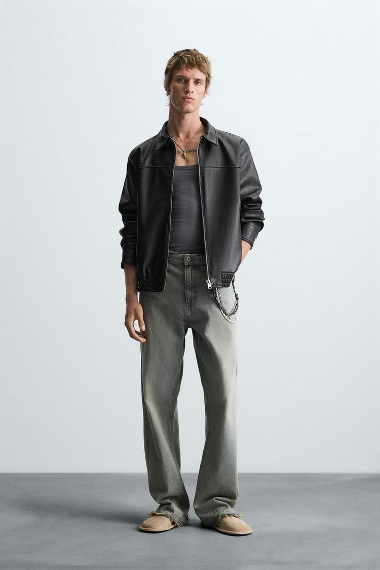 Man wearing a Gigavibe vegan leather bomber jacket in India, gray shirt, and jeans on a plain background