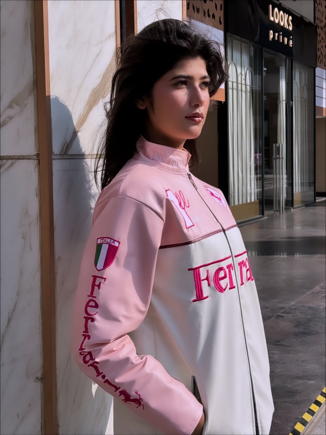Woman wearing a pink and white jacket Rear view of pink Ferrari racing jacket with logo design