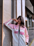 women wearing a Pink Ferrari jacket streetwear look by Gigavibe, standing against a building.