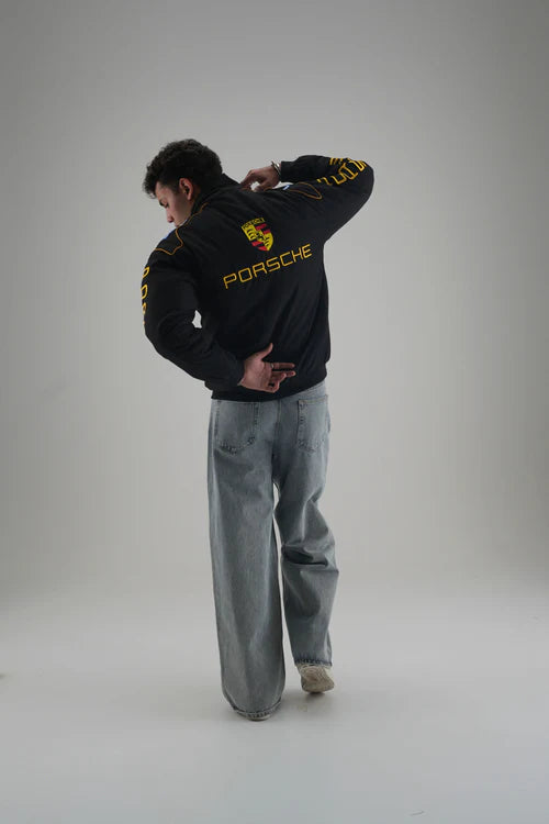 Man wearing Gigavibe Porsche Jacket Embroidered black racing jacket with yellow logo and text on back