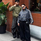 Urban city setting with the male and female models styling the massive Olive Green and Dark Grey bombers. Displays the perfect hybrid of high fashion runway draping and raw Gen Z streetwear utility.