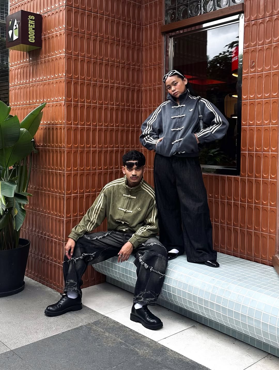 Side angle of the streetwear couple wearing the heavy earth-tone suede bombers. The extreme dropped shoulder profile expertly highlights the oversized genderless boxy fit meant for modern fashion.