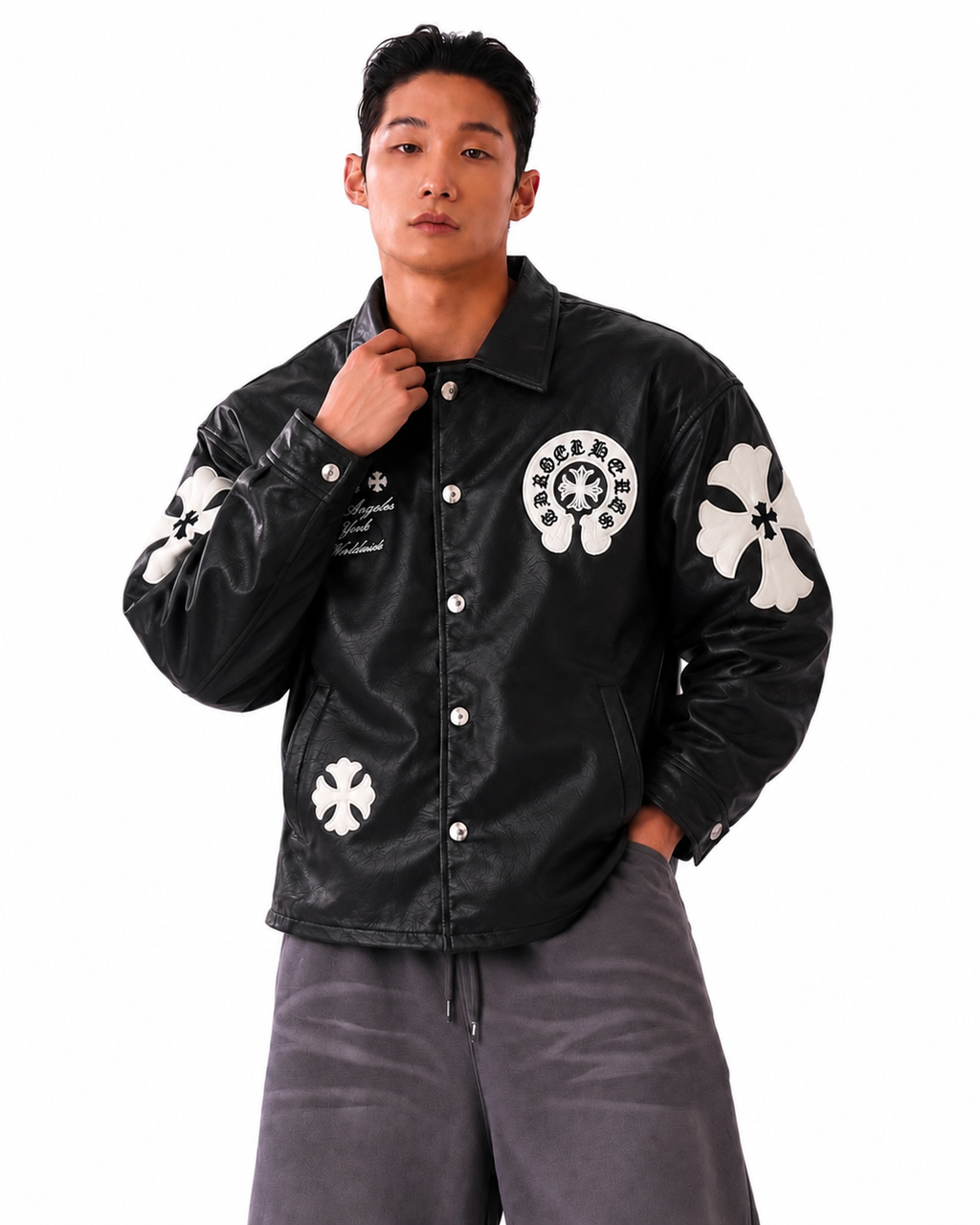 Front view of a boy styling the black cross patch trucker jacket, showing the deep side welt pockets and silver snap fasteners