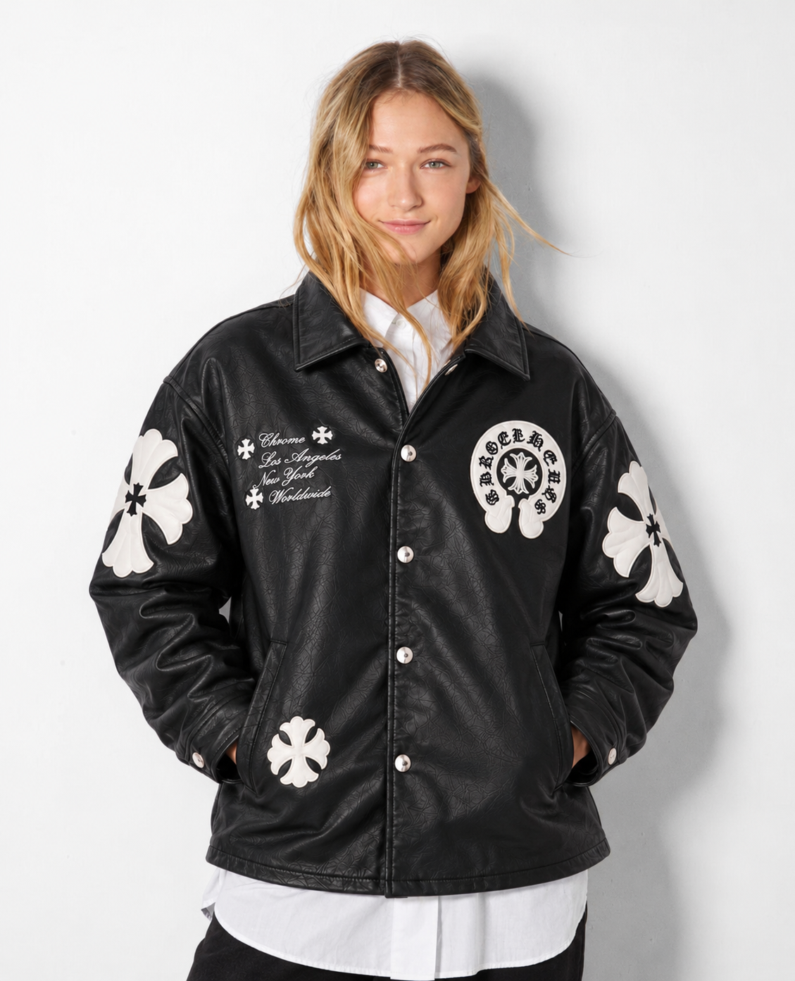 Streetwear front lifestyle angle of a girl styling the black cross patch faux leather jacket with washed wide-leg denim