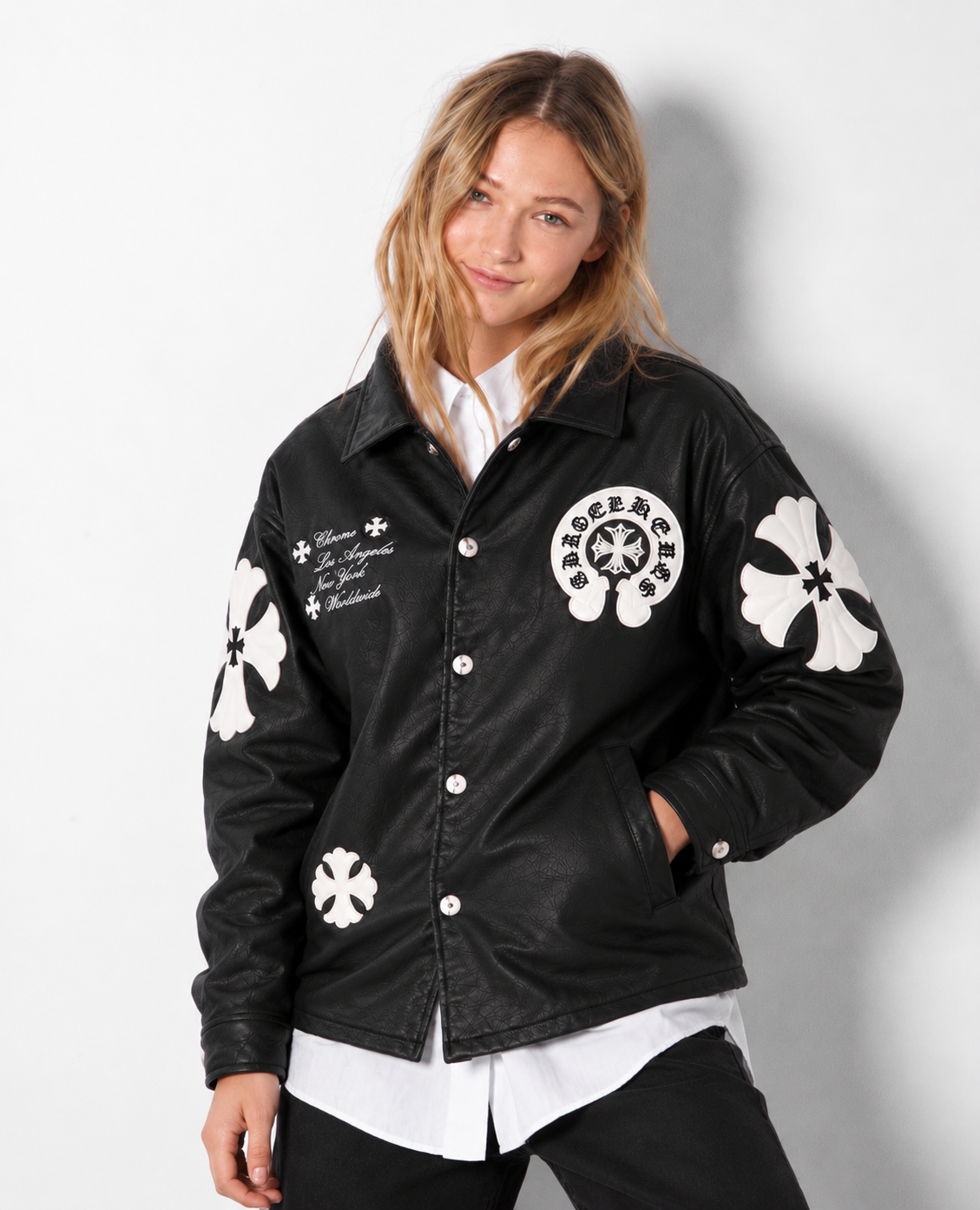 Female model wearing the unisex black Gothic cross patch leather jacket from the front, showing the clean drop-shoulder cut