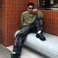 Full body outfit styling showing the male model utilizing the Olive Green Suede Bomber perfectly. Anchored with massive baggy cargo pants to emphasize the aggressive horizontal Gen-Z frame.