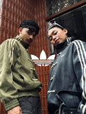 Male and female models posing in matching oversized vegan suede knot jackets in Olive and Grey. Showcasing the flawless unisex aesthetic and high-end matching streetwear couples outfit at Gigavibe.