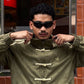 Side profile of the male model executing the box-cut aesthetic in the Olive Green Custom Knot bomber. Clearly shows the heavy 3-stripe sleeve embroidery utilized in premium vintage racing outerwear.