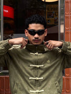 Side profile of the male model executing the box-cut aesthetic in the Olive Green Custom Knot bomber. Clearly shows the heavy 3-stripe sleeve embroidery utilized in premium vintage racing outerwear.