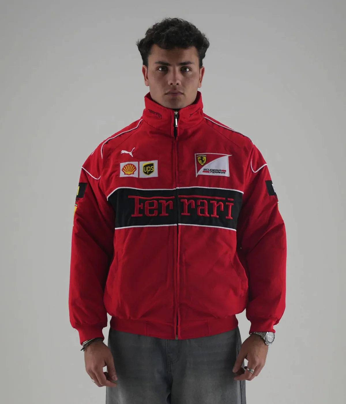 Male model wearing the unisex red Ferrari embroidered racing jacket, showcasing the structured drop-shoulder drape and vibrant polyester shell