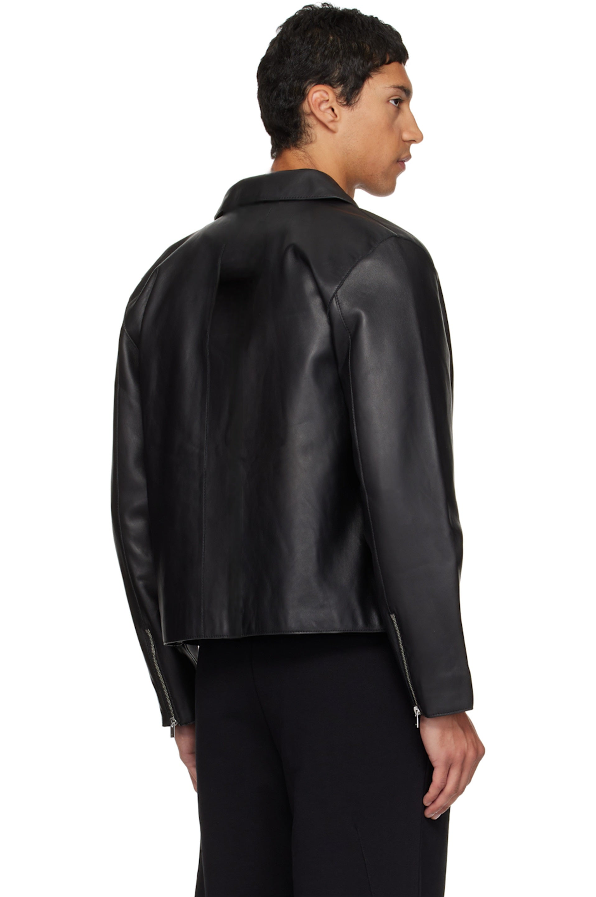 Side and back profile of the minimalist black leather moto jacket. Showcases exactly where the cropped hem hits the waistline to emphasize the oversized streetwear architecture, ensuring a perfect gender-neutral darkwear silhouette.