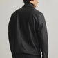 Side and profile view of the minimalist black leather box-cut jacket. Showcases precisely where the extreme dropped shoulder seam rests to emphasize the oversized streetwear architecture, ensuring a perfect gender-neutral darkwear silhouette.
