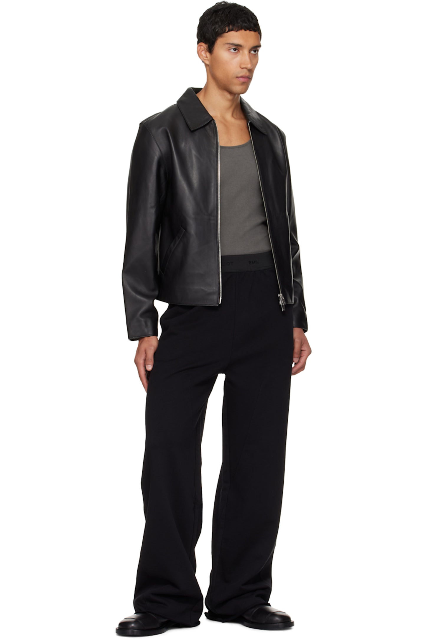 Full body lifestyle shot of the model wearing the black oversized cropped jacket open over a streetwear base layer