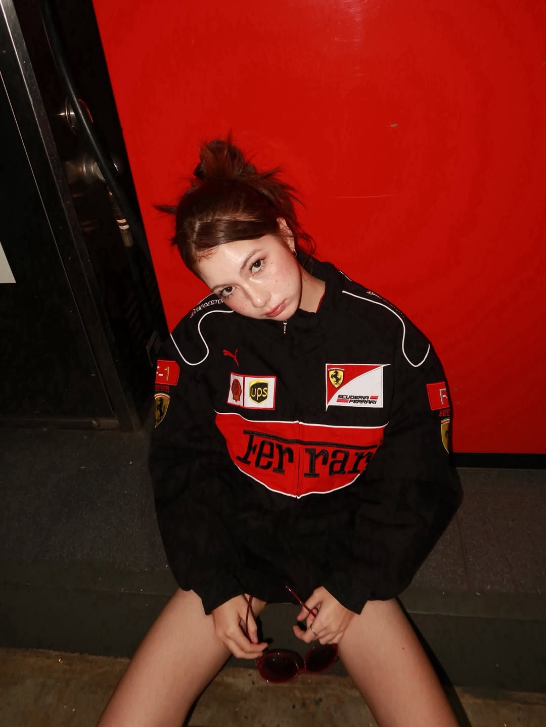 Side profile shot of female model displaying the detailed threadwork embroidered sponsor badges along the black polyester sleeve