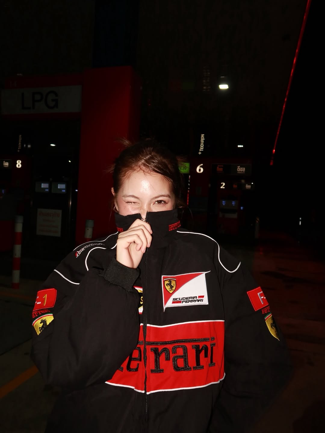 Full length streetwear shot of a girl styling the black embroidered Ferrari bomber jacket with washed grey baggy jeans and chunky boots