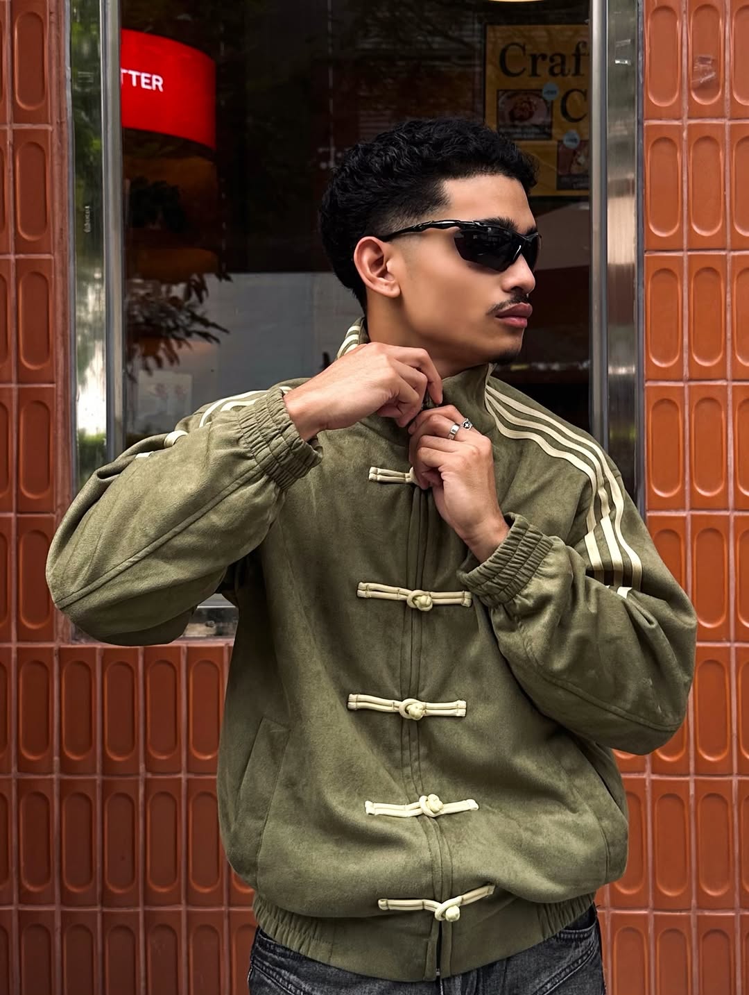 Rear perspective of the male model demonstrating the sheer broadness of the extreme dropped shoulders on the Olive Green jacket, perfectly executing the hyper-wide streetwear visual.