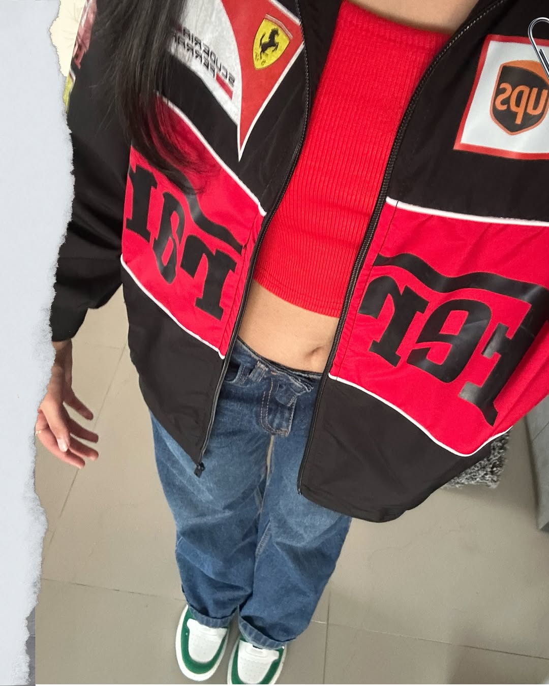 lose-up of the Y2K streetwear Ferrari F1 jacket in black, worn open over a red crop top. Features the breathable micro-mesh red lining and striking high-density chest graphics for aesthetic motorsport clothing India.